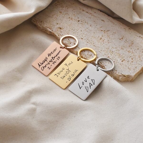 Pack of 3 engraved stainless steel keychains with personalized designs."