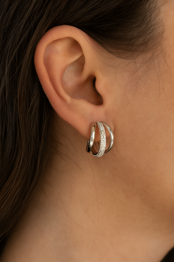 "Woman wearing silver triple hoop earrings with crystal detailing, showcasing elegant and modern jewelry style"