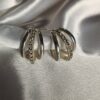 Elegant silver triple hoop earrings with crystal detailing on satin background"